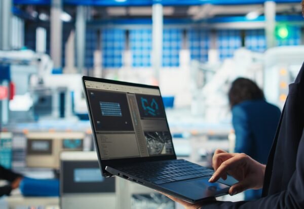 Photovoltaics factory worker analyzing data, reviewing system health metrics with laptop. Solar panels manufacturing plant employee troubleshooting technical issues using notebook, camera A close up